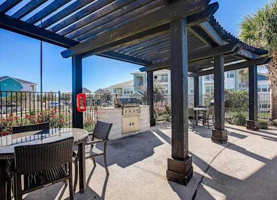 Pergola-covered patio dining area next to built-in grill station.