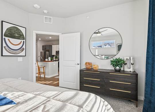 A bedroom with a large bed, a dresser, and a mirror.