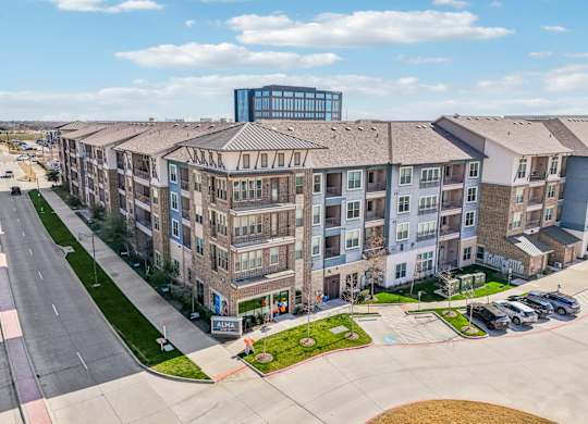 A large apartment complex with a parking lot in front.