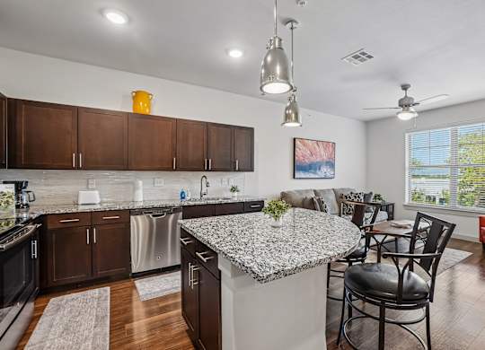 A kitchen with a granite countertop and a dining table with chairs.