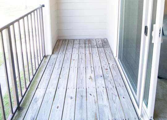A white door is on the right side of a wooden deck.