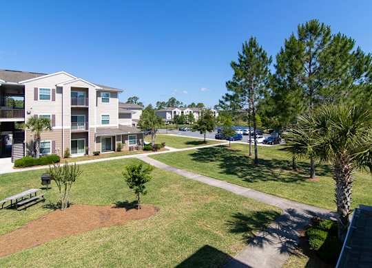 Apartment complex with a green lawn and trees.