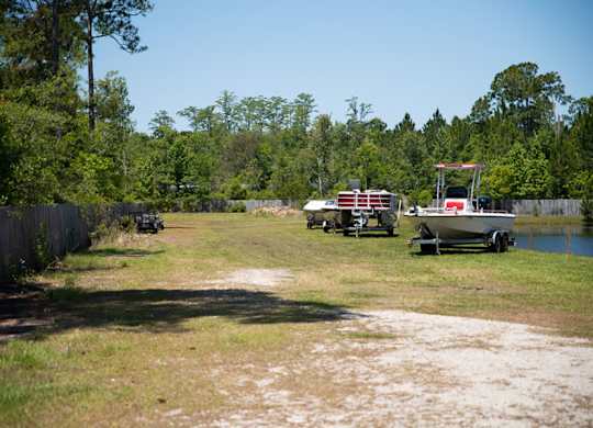 A boat is parked on a trailer in a grassy area.