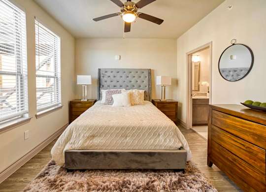 A bedroom with a large bed, a ceiling fan, and a rug on the floor.