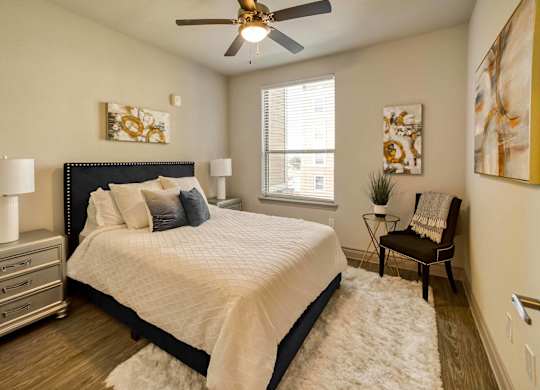 A bedroom with a bed, a chair, and a ceiling fan.