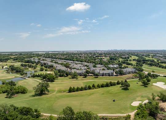 Wide aerial view of golf course fairways, ponds, and surrounding Carrollton neighborhood.