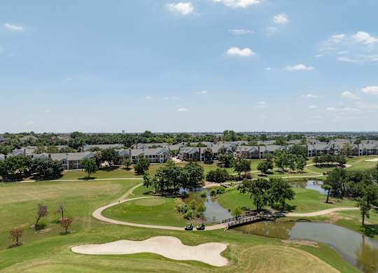 Aerial view of Coyote Ridge golf course, ponds, bridge, and nearby residences.