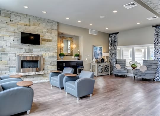 A living room with a stone fireplace and grey couches.
