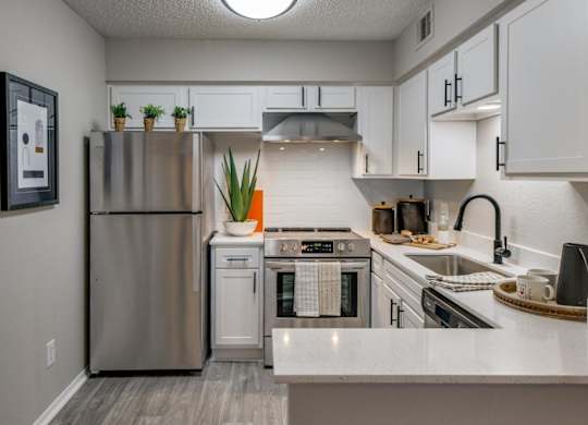 Bright kitchen with white shaker cabinets, stainless appliances, and quartz peninsula seating.