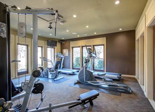 Fitness center with treadmills, elliptical machines, and strength equipment in a bright room