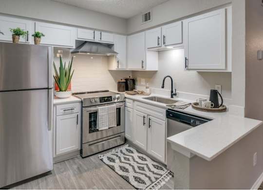 Modern L-shaped kitchen featuring breakfast bar, stainless dishwasher, and matte-black faucet.