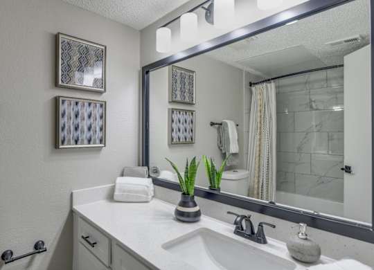 Updated bathroom vanity with oversized mirror, modern lighting, and black hardware.