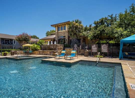 Resort-style pool with tanning ledge, lounge chairs, and landscaped courtyard views.