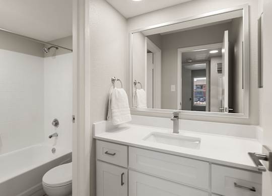 Contemporary bathroom with white vanity, framed mirror, and tub-shower combination at Heritage at Valley Ranch.