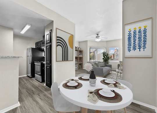 Open dining and living area with adjacent kitchen, large window, and wood-style flooring.