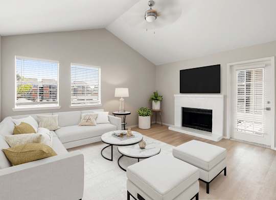 Bright living room with vaulted ceiling, fireplace, large windows, and soft neutral finishes.