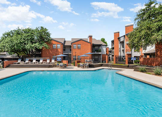 Community pool with sundeck loungers, shaded tables, and landscaped courtyard setting.