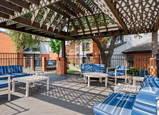 Pergola-covered outdoor lounge with cushioned seating beside the pool deck.