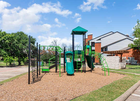 Apartment community playground with climbing structure, slides, and open lawn area.
