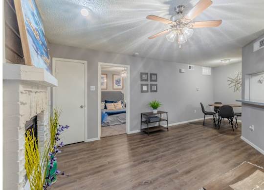 A room with a fireplace, a ceiling fan, and a dining table with chairs.