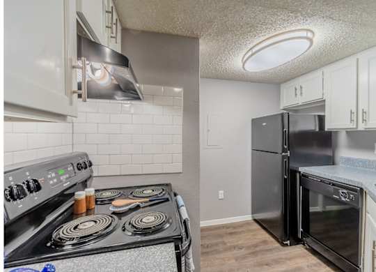 A kitchen with a black stove top oven and a black refrigerator.