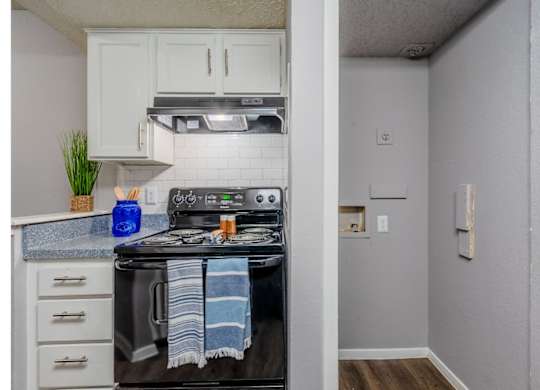 A kitchen with a black stove top oven and white cabinets.