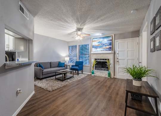 A living room with a grey couch and a wooden floor.