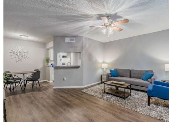 A living room with a grey couch, a blue chair, and a wooden floor.
