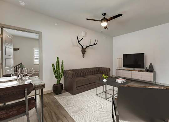 A living room with a brown couch, a black chair, a wooden dining table, and a deer head mounted on the wall.