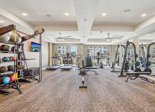 a gym with weights and cardio equipment in a building with windows