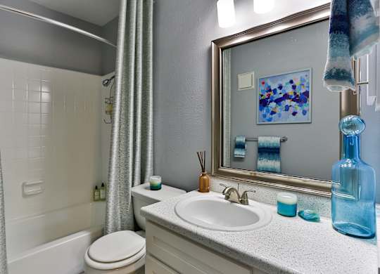 A bathroom with a white toilet, a sink, and a mirror.