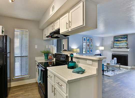A kitchen with black appliances and white cabinets.