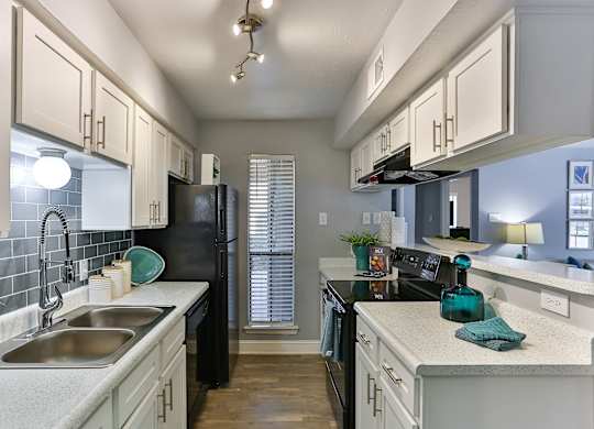 A kitchen with black appliances and white cabinets.