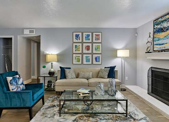 A living room with a blue chair and a glass coffee table.