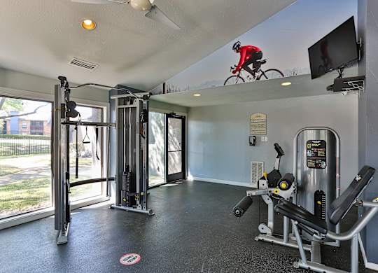 A gym with a television and a person on a bicycle above.
