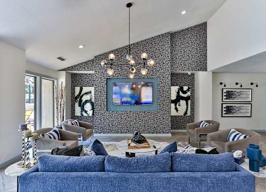 A living room with a blue couch and a painting on the wall.