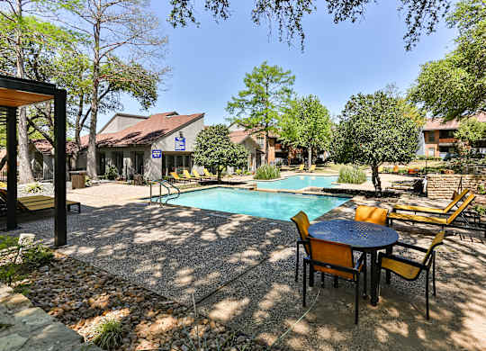 A pool surrounded by chairs and trees.