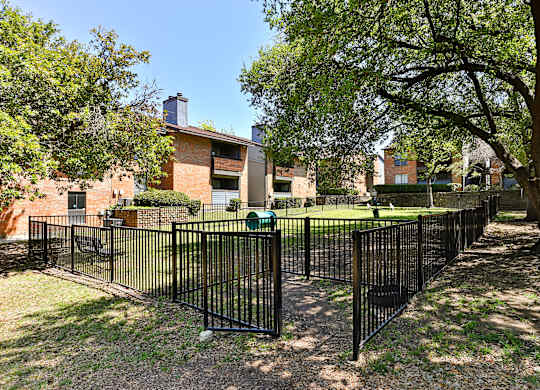 A black metal fence surrounds a green lawn.