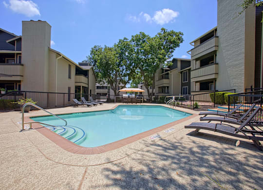A swimming pool surrounded by apartment buildings on a sunny day.