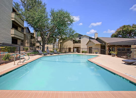 A large swimming pool surrounded by a fence and buildings.
