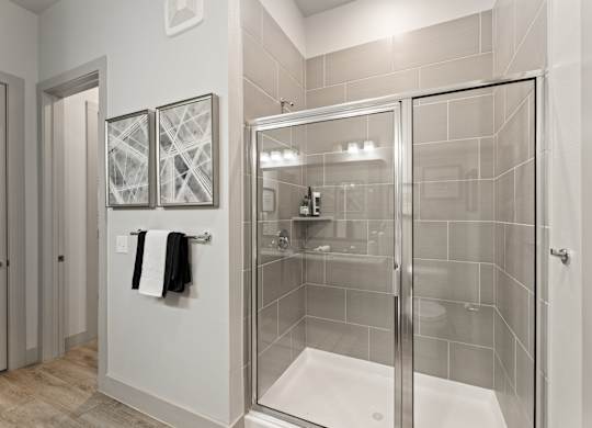 A bathroom with a walk-in shower and two towels hanging on the wall.