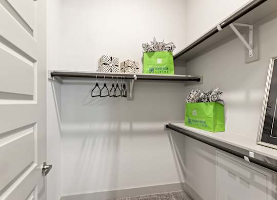 A white closet with two shelves and two green boxes on top.