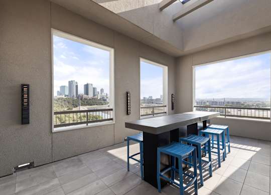 A modern kitchen with a bar stool and a view of the city.