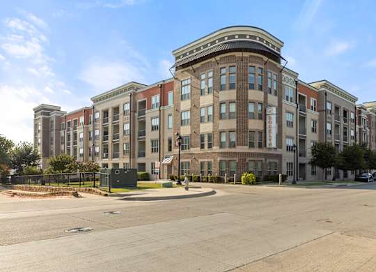 A large, multi-story building with a flat roof and a parking lot in front.