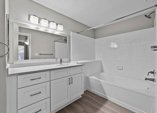Bathroom with white vanity, integrated sink, and tub-shower combination with tile surround.