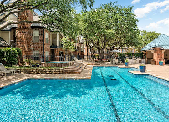 Large Dallas, TX pool deck with lap lanes, shaded pavilion, and surrounding trees.