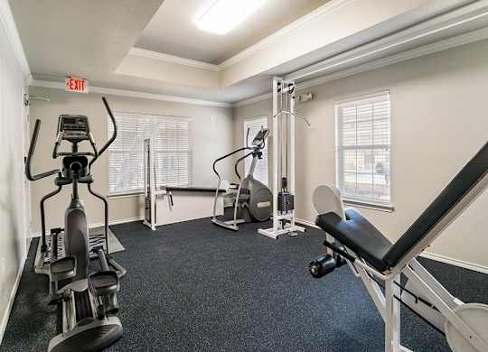 A well-equipped gym with a variety of machines and a bench.