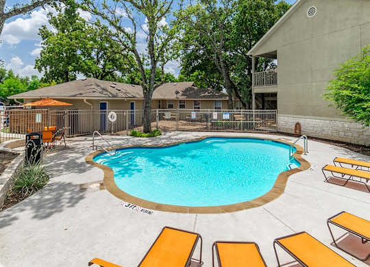 A small pool surrounded by a concrete patio and wooden sun loungers.