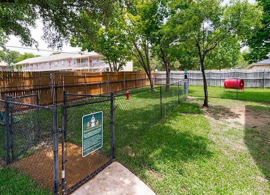 A sign is posted on a fence in a green space.