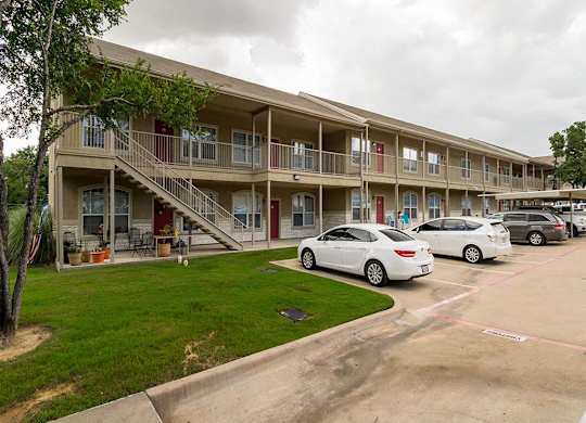 A white car is parked in a parking lot in front of a building.